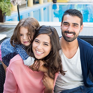 family smiling beside pool