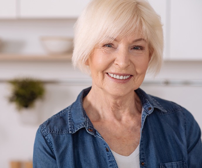 Senior woman in denim jacket smiling in kitchen