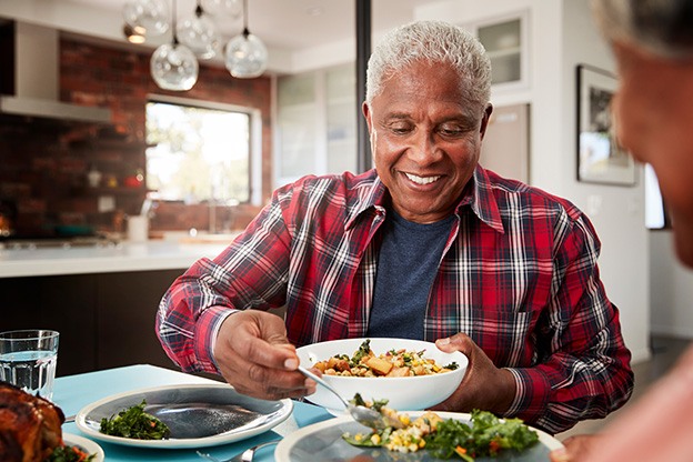 Senior man filling bowl at dinner table