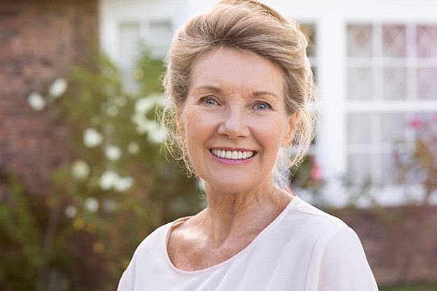 Senior woman in white shirt standing outside and smiling