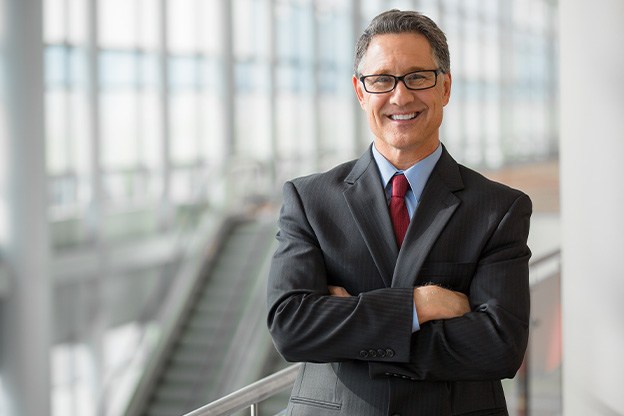 Senior man in suit smiling with arms folded