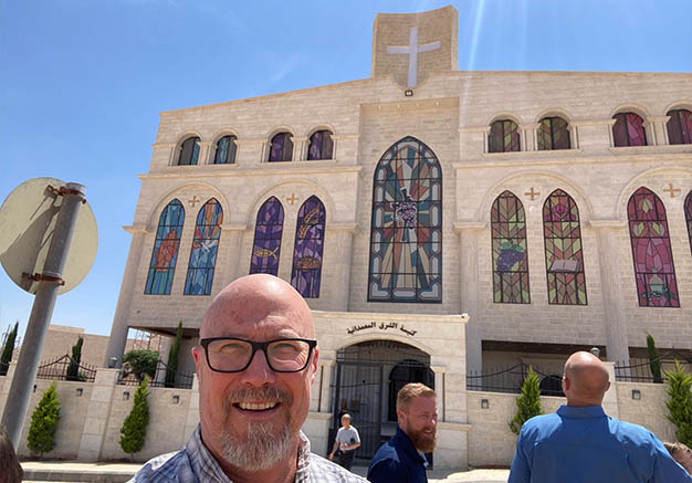 Man smiling in front of a church