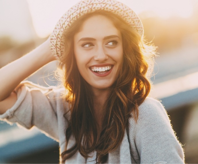 Woman with hat smiling after visiting cosmetic dentist in Arlington