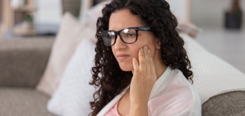 Woman with glasses rubbing her jaw