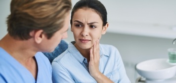 Woman at dental office rubbing her jaw