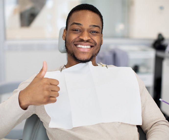 Man in dental chair smiling and giving a thumbs up