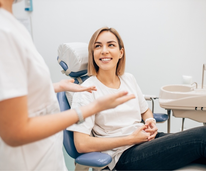 Woman sitting in dental chair smiling at dentist