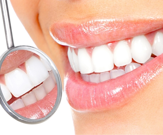 Checking smile with dental mirror after teeth whitening in Arlington