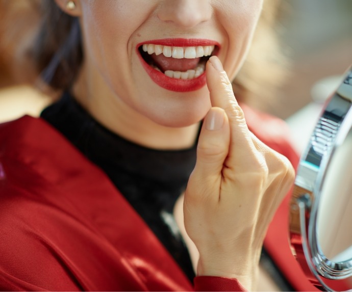 Woman checking smile in handheld mirror