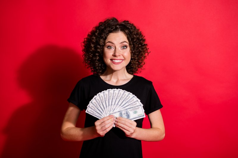 woman holding a fan of money and smiling